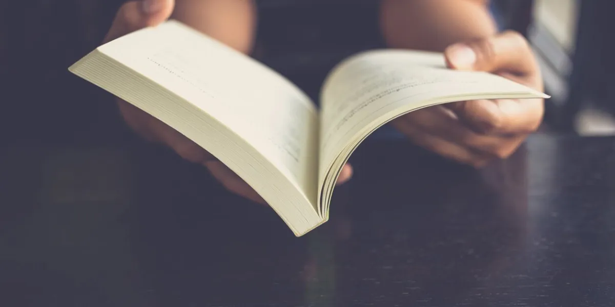 woman place her arms on her lap and open book to read