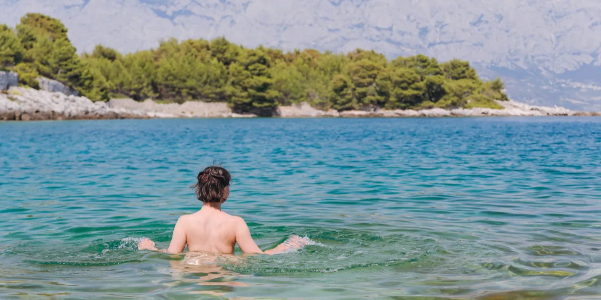 naked woman is swimming in the sea in croatia naturism nudism