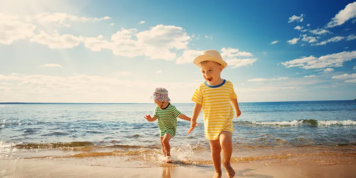 boy and girl playing on the beach on summer holidays children in nature with beautiful sea, sand and blue sky happy kids on vacations at seaside running in the water