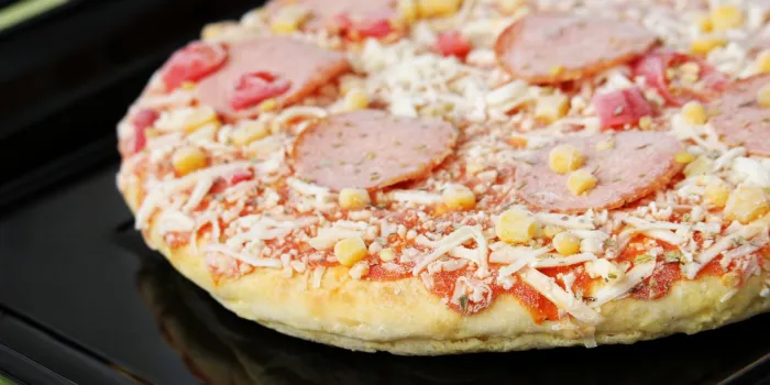 frozen pizza with salami, cheese, corn and pepper