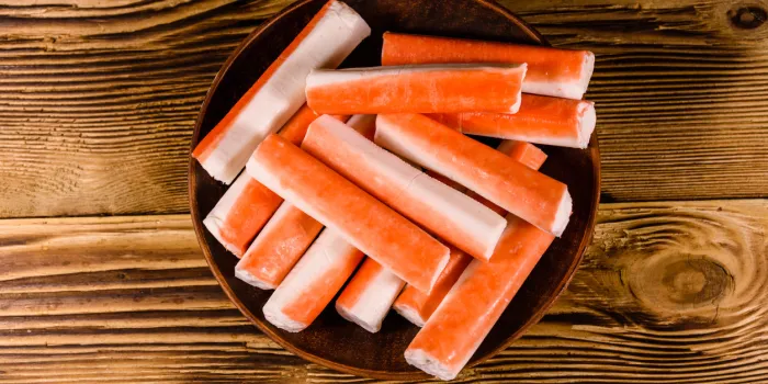 ceramic plate with crab sticks on rustic wooden table top view
