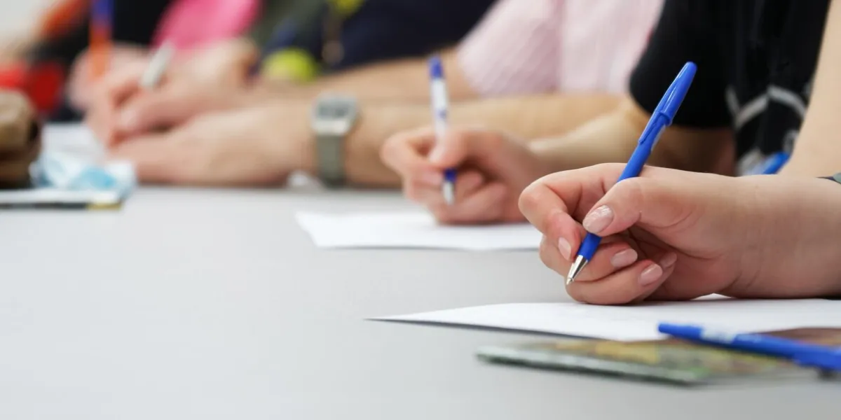 the girls write with fountain pens on sheets of paper concept for college exam, filling out forms and questionnaires web banner close-up without a face