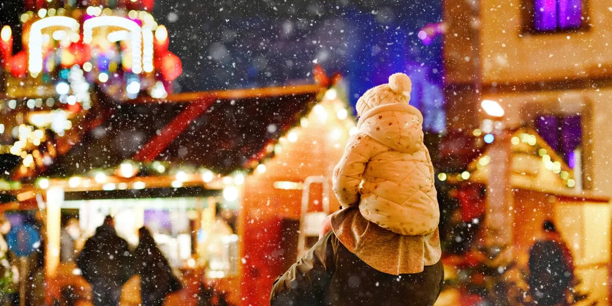 little preschool girl sitting on shoulder of father on christmas market in germany happy toddler child and man observing traditional decorated pyramid happy family, bonding, love family xmas time