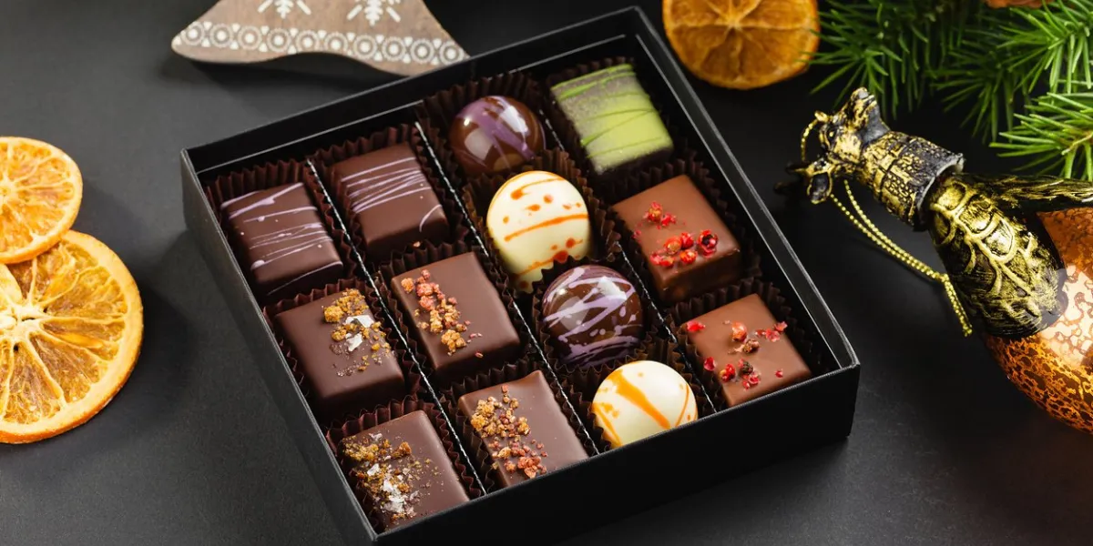 assortment of colorful handmade chocolate candies in black box with christmas decorations exclusive luxury bonbons product concept for chocolatier