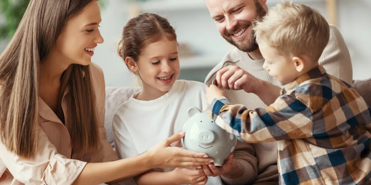 financial planning happy family mother father and children with piggy bank at home