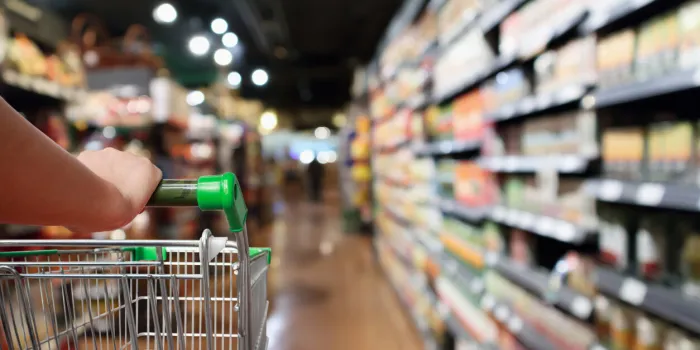 woman hand hold shopping cart with abstract blur supermarket aisle background