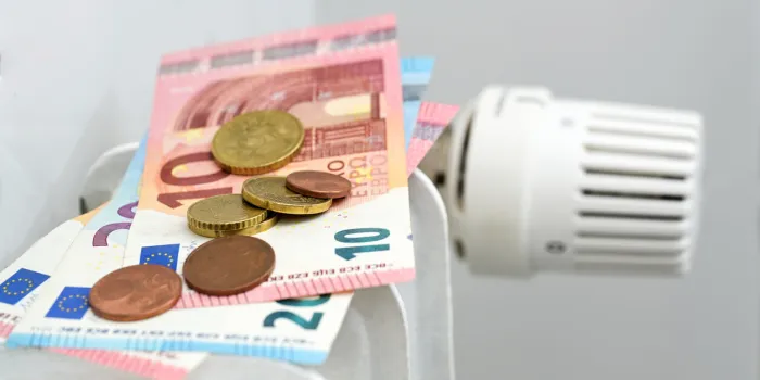 euro banknotes and coins on a heating radiator, concept for rising energy prices and inflation, copy space, selected focus, narrow depth of field