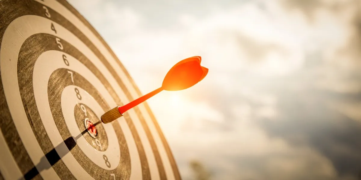 close up shot red darts arrows in the target of dartboard center on dark blue sky background business target or goal success and winner concept