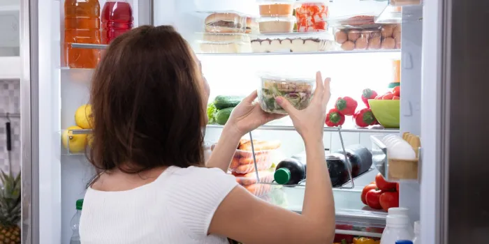 rear view of a young woman taking food from refrigerator
