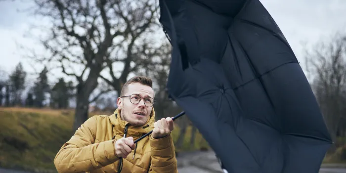 man holding broken umbrella in strong wind during gloomy rainy day themes weather and meteorogy n
