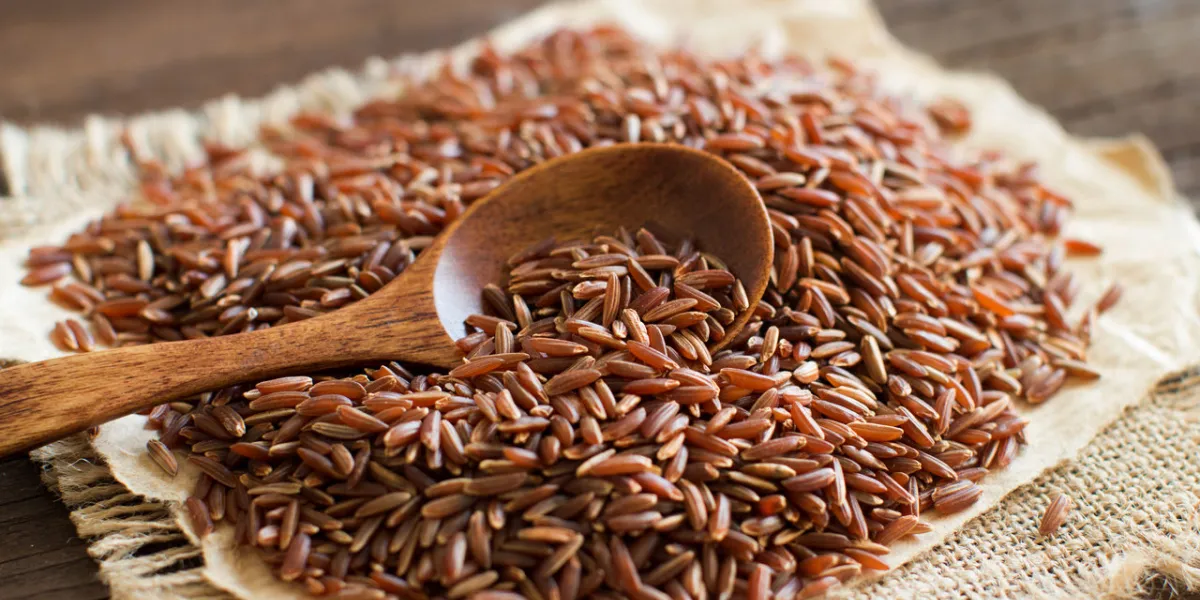 uncooked red rice with a wooden spoon close up