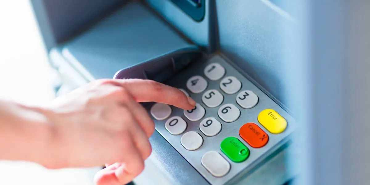 close-up of hand entering pin pass code for a money transfer, on a atm bank machine keypad outside