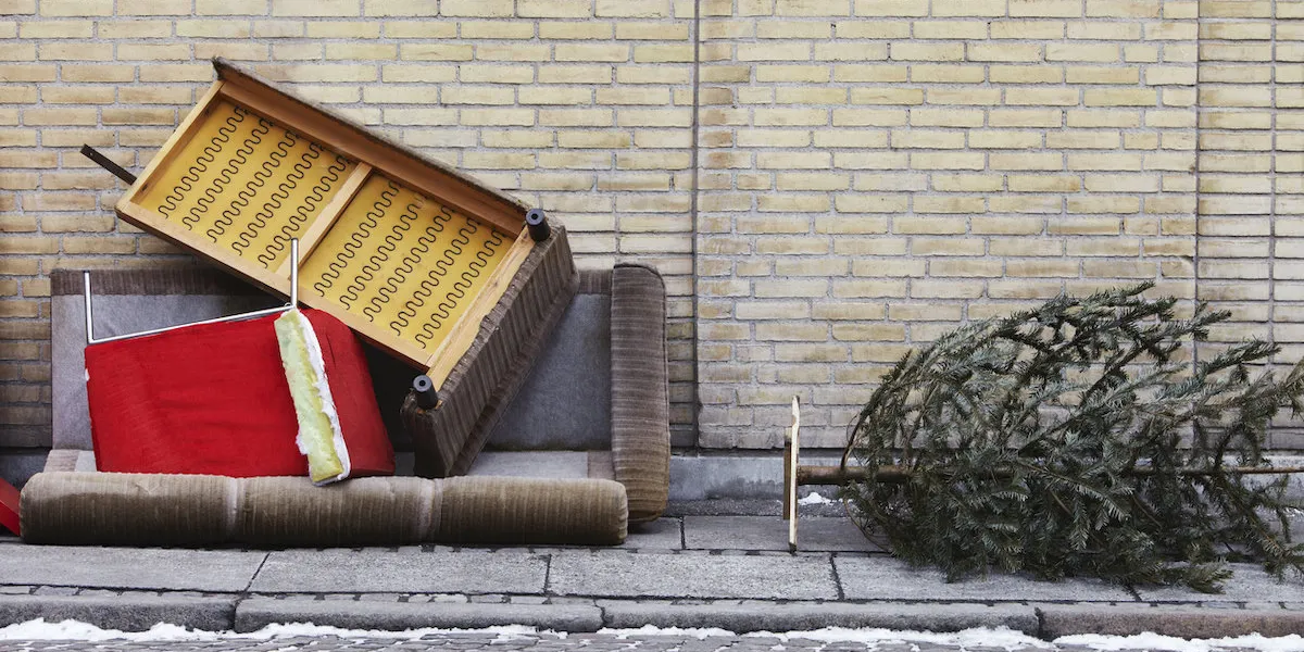 broken furniture and christmas tree left on pavement