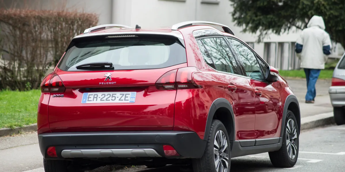 mulhouse - france - 22 march 2021 - rear view of red peugeot 2008, the famous french suv car parked in the street with man on background