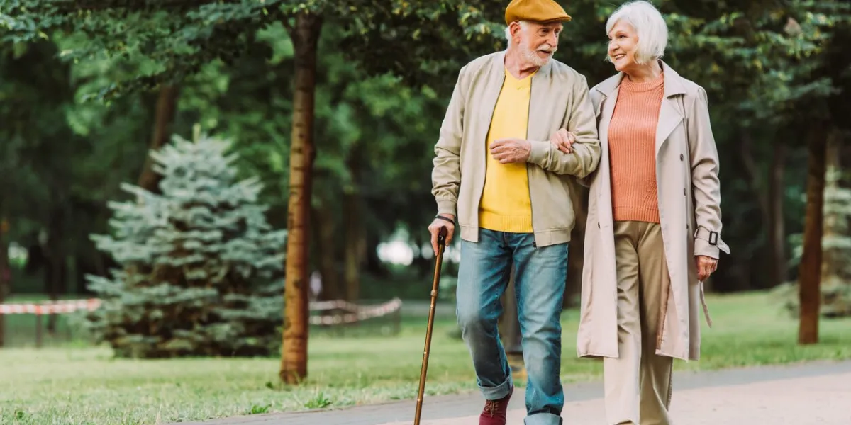 senior couple smiling while walking on path in park