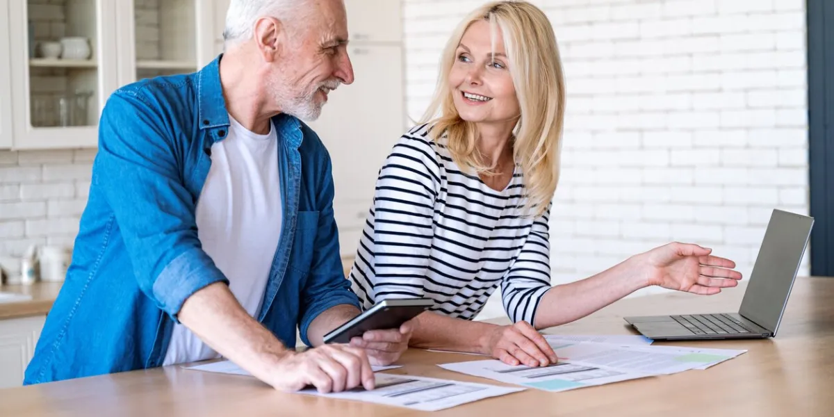 mature wife and husband checking documents with tax, pension savings and internal bills doing payments online and discussing family budget calculating funds for purchase new home or car