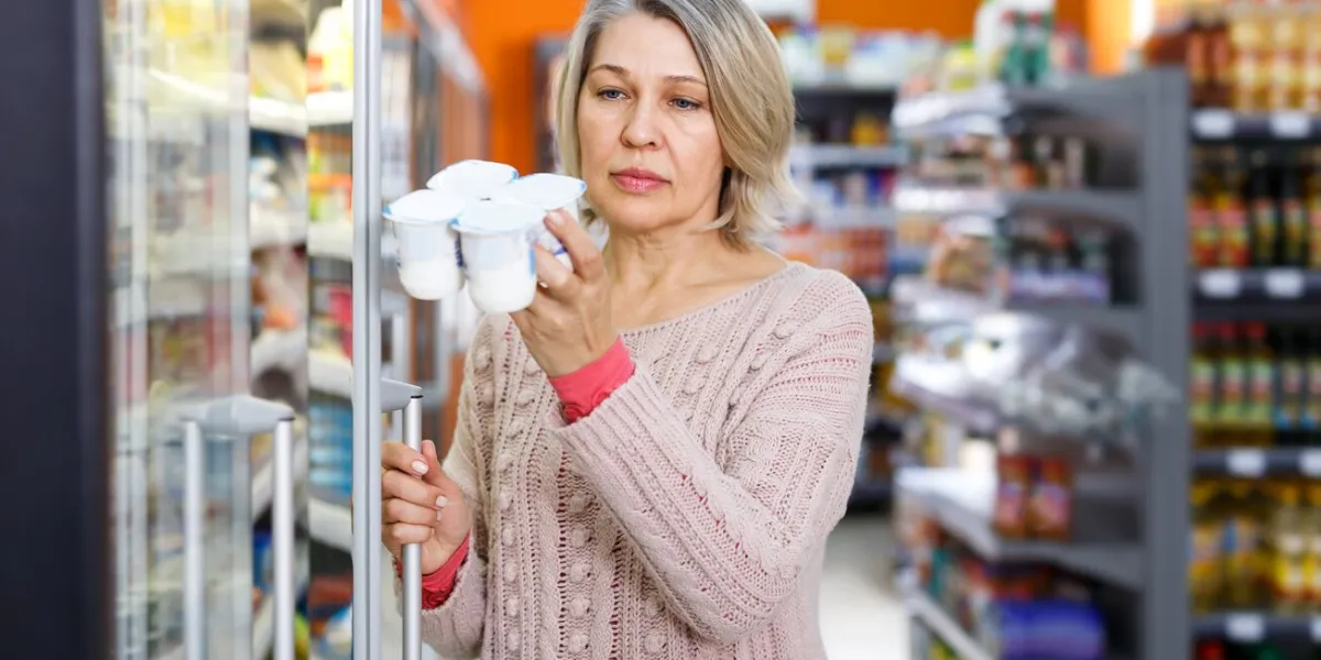 casual adult woman shopping for milk products at supermarket food department