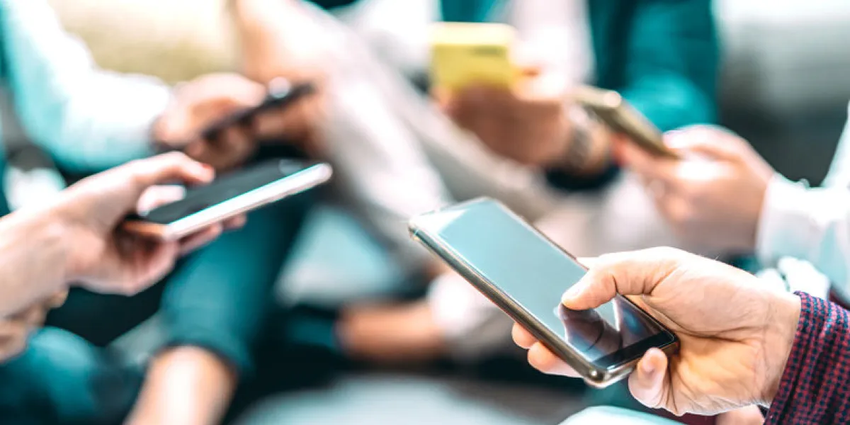 close up of people using mobile smart phones - detail of friends sharing photos on social media network with smartphone - technology concept and cellphone culture with selective focus on right hand