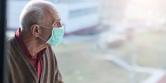 aged pensioner man with gray hair wearing medical facemask looking through window health care concept