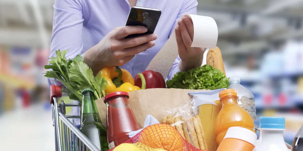 woman checking the grocery receipt using her smartphone
