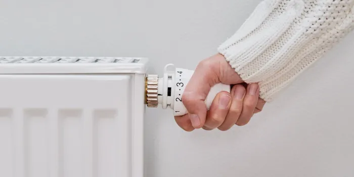 woman adjusting temperature on heating radiator, energy crisis concept in europe, rising costs in private households for gas bill due to inflation and war