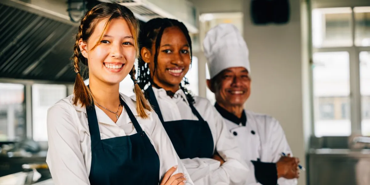 in a professional kitchen smiling chefs in uniform pose for a portrait displaying expertise togetherness and teamwork teaching colleagues working together