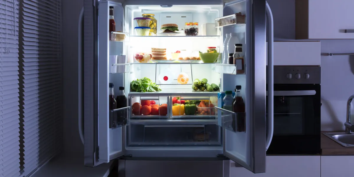 open refrigerator full of juice and fresh vegetables in kitchen