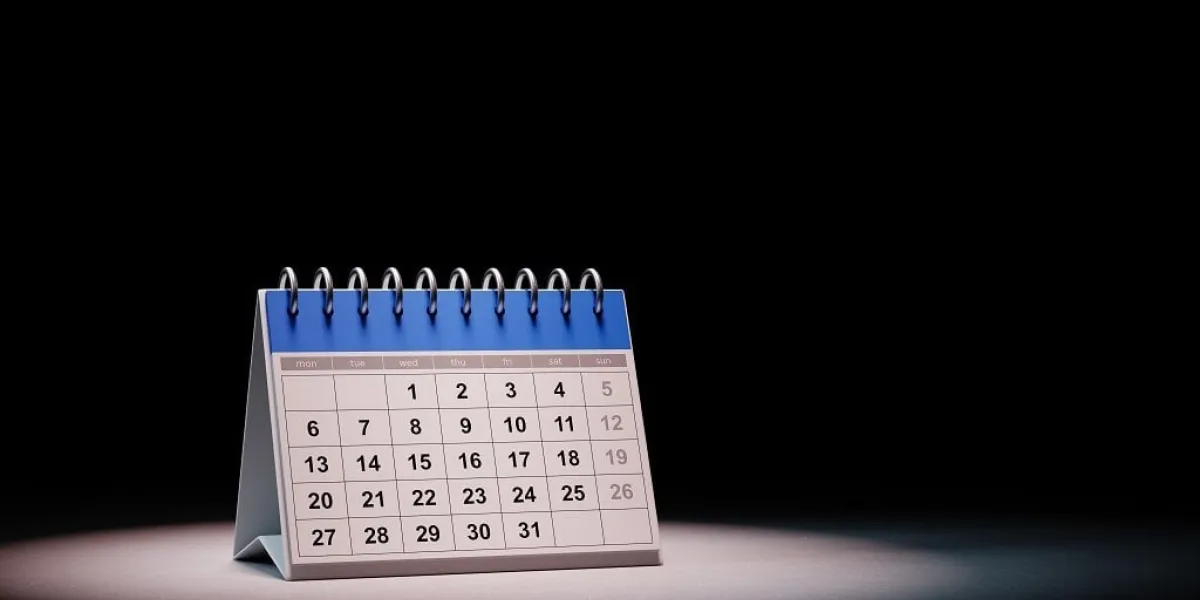 blue and white desk calendar spotlighted on black background with copy space 3d illustration