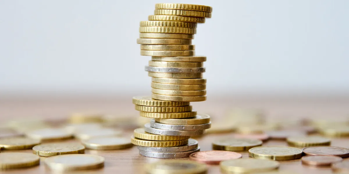 pile of coins on a wooden table with shallow depth of field