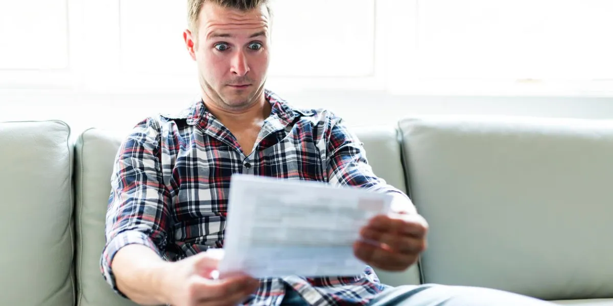 a shocked man holding some documents in the livingroom