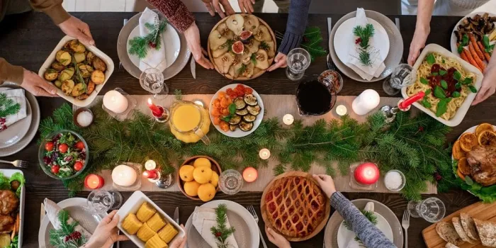 top view of hands of family members holding plates with homemade food and desserts while serving festive table before christmas dinner