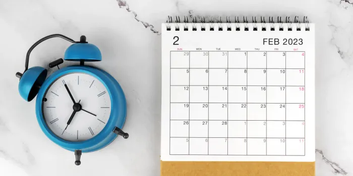 february 2023 flat lay calendar and alarm clock