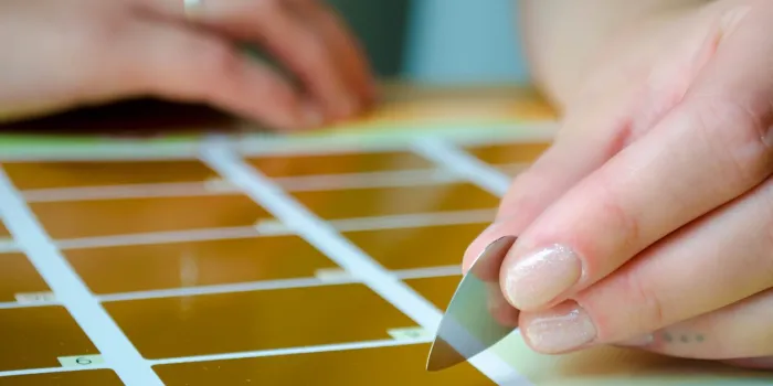 young girl is holding a guitar pick and is about to scratch off a calendar with gold coating