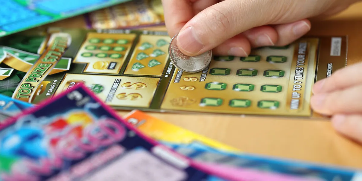 coquitlam bc canada - june 15, 2014   woman scratching lottery ticket called monopoly it's published by bc lottery corporation has provided government sanctioned lottery games