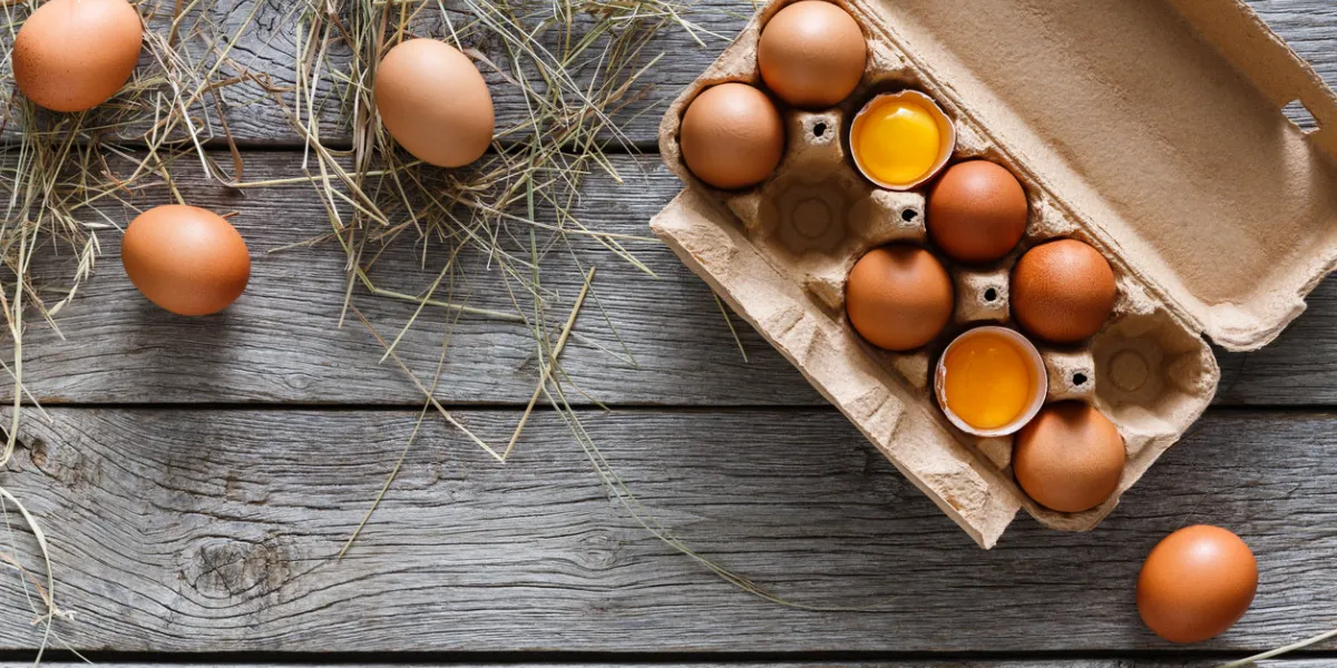 fresh chicken eggs background brown and white eggs in craft carton pack on hay at rustic wood table with copy space top view natural healthy food and organic farming concept