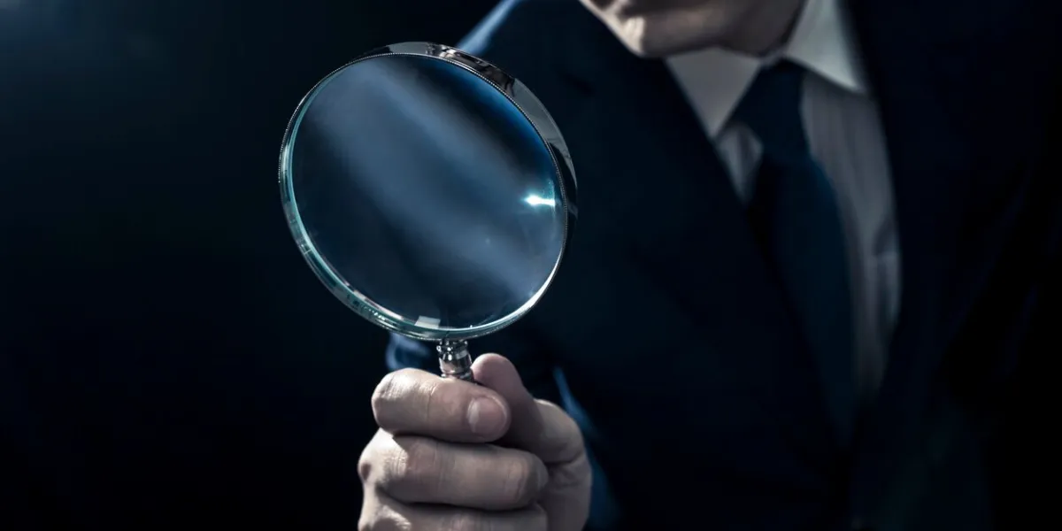 male businessman peering through magnifying glass