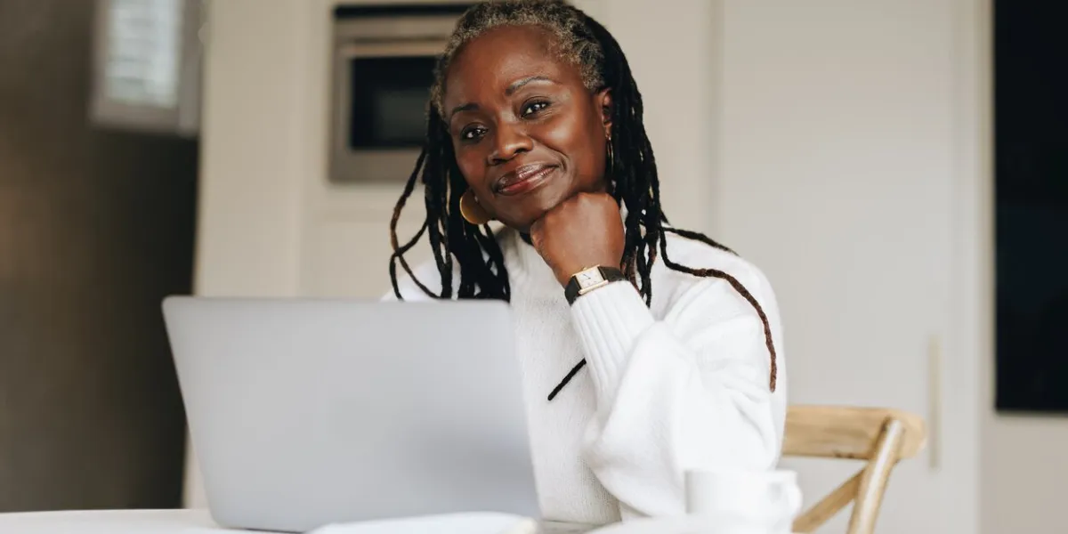 senior businesswoman looking at the camera while working on a laptop at home mature businesswoman doing online freelance work in her home office