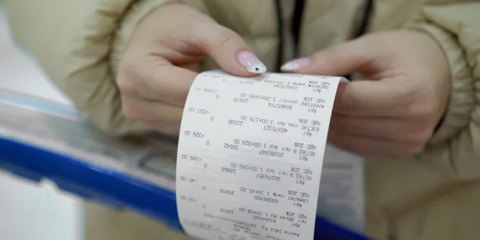 the buyer holds a purchase receipt in his hands, checks purchases and prices woman in a supermarket with a shopping cart girl with paper bill in store